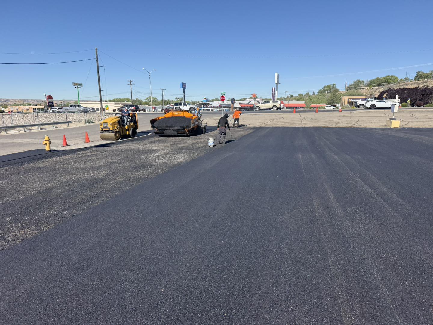 Reliable Asphalt crew operating paver and roller on a commercial lot